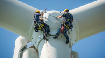Two people rappelling down a wind turbine