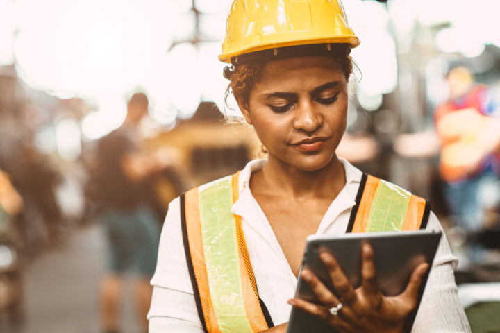 Woman in hard hat looking at device